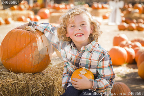 Image of Little Boy Sitting and Holding His Pumpkin at Pumpkin Patch
