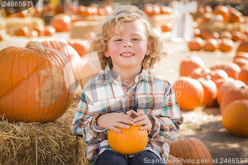 Image of Little Boy Sitting and Holding His Pumpkin at Pumpkin Patch
