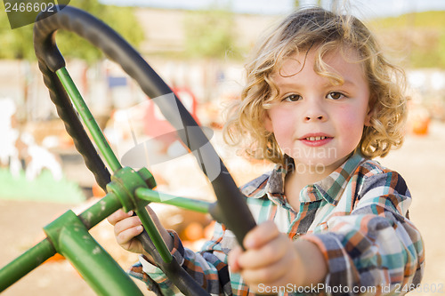 Image of Adorable Young Boy Playing on an Old Tractor Outside