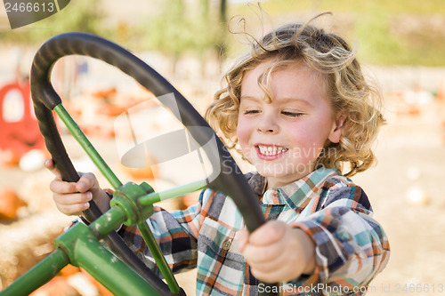 Image of Adorable Young Boy Playing on an Old Tractor Outside