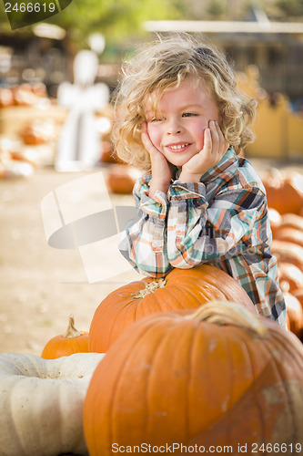 Image of Little Boy Smiles While Leaning on Pumpkin at Pumpkin Patch