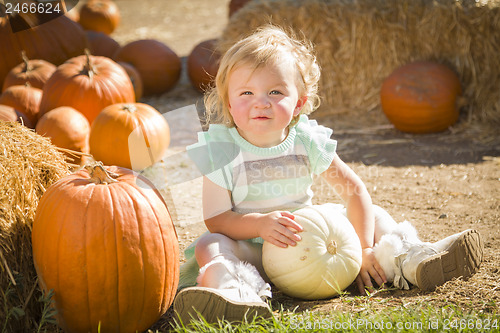 Image of Adorable Baby Girl Holding a Pumpkin at the Pumpkin Patch
