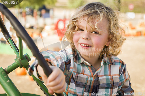 Image of Adorable Young Boy Playing on an Old Tractor Outside
