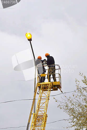 Image of Electricians repair a streetlight.