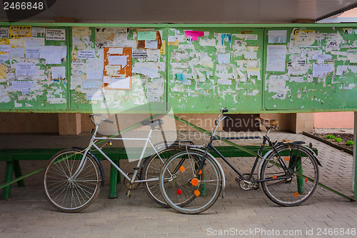Image of Two Old Bicycle Leaning Against A Bulletin Board On The Street