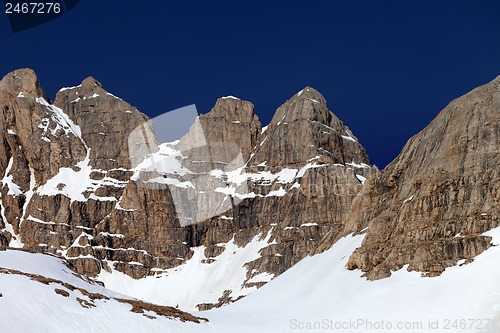 Image of Rocks in snow and blue cloudless sky