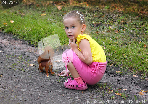 Image of little girl feeding squirrel with nuts