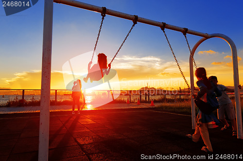 Image of child playing swing against sunset