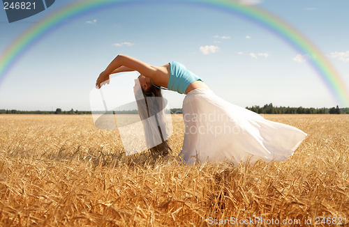 Image of stretching woman in the meadow with rainbow