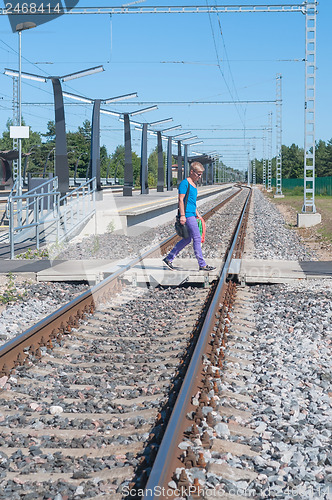 Image of Man walking across the railroad tracks