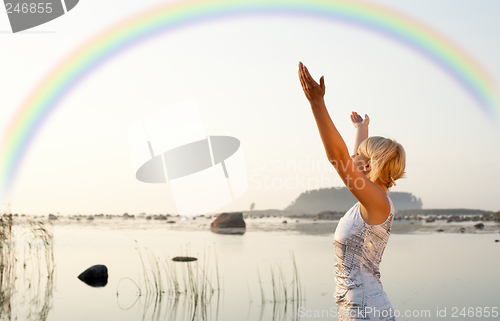 Image of pretty blond raising hands to the rainbow