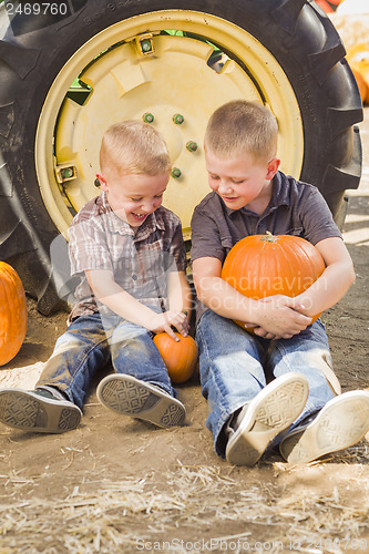 Image of Two Boys Holding Pumpkins Talking and Sitting Against Tractor Ti