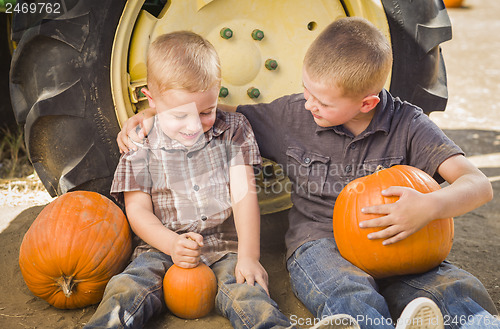 Image of Two Boys Holding Pumpkins Talking and Sitting Against Tractor Ti