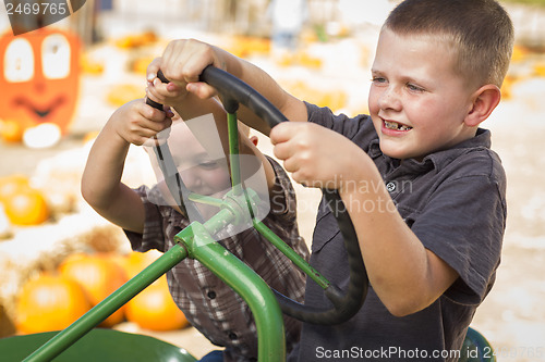 Image of Adorable Young Boys Playing on an Old Tractor Outside