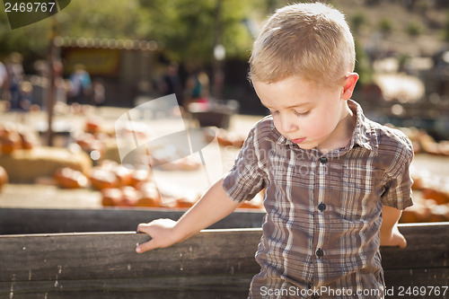 Image of Sad Boy at Pumpkin Patch Farm Standing Against Wood Wagon
