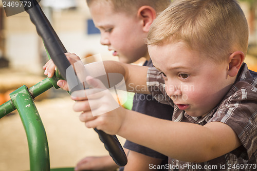 Image of Adorable Young Boys Playing on an Old Tractor Outside