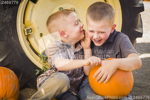 Image of Two Boys Sitting Against Tractor Tire Holding Pumpkins Whisperin