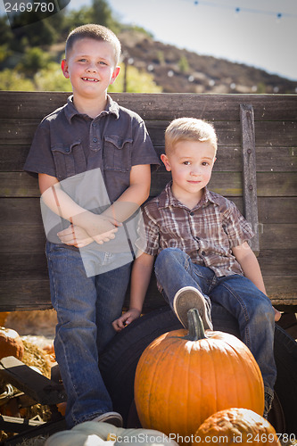 Image of Two Boys at the Pumpkin Patch Against Antique Wood Wagon