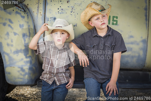 Image of Two Young Boys Wearing Cowboy Hats Leaning Against Antique Truck