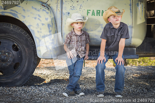 Image of Two Young Boys Wearing Cowboy Hats Leaning Against Antique Truck