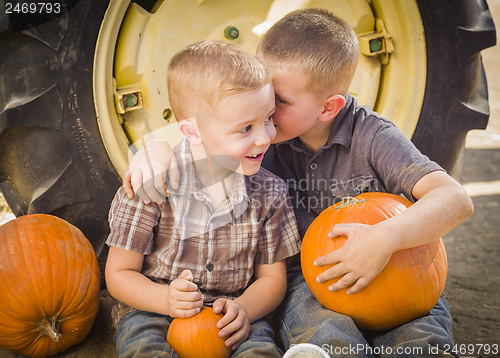 Image of Two Boys Sitting Against Tractor Tire Holding Pumpkins Whisperin