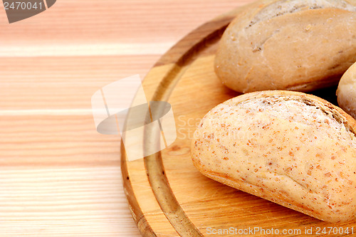 Image of Closeup of fresh bread rolls on a wooden board