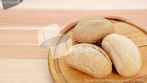 Image of Three crusty petit pain on a bread board