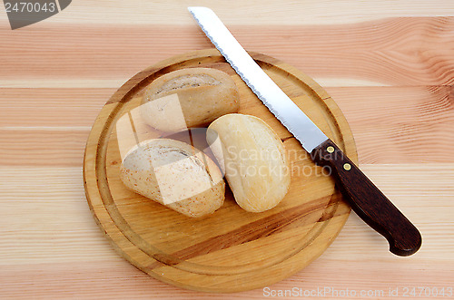 Image of Three fresh rolls with a bread knife