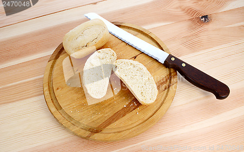 Image of Fresh rolls, whole and halved, with bread knife