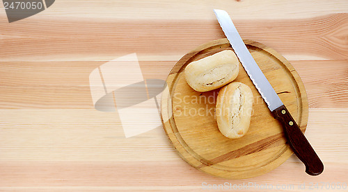 Image of Two bread rolls, a knife and wooden cutting board