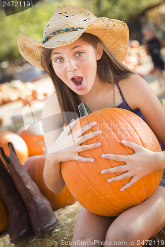 Image of Preteen Girl Holding A Large Pumpkin at the Pumpkin Patch
