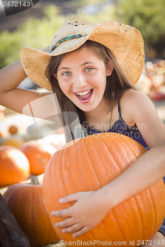 Image of Preteen Girl Holding A Large Pumpkin at the Pumpkin Patch
