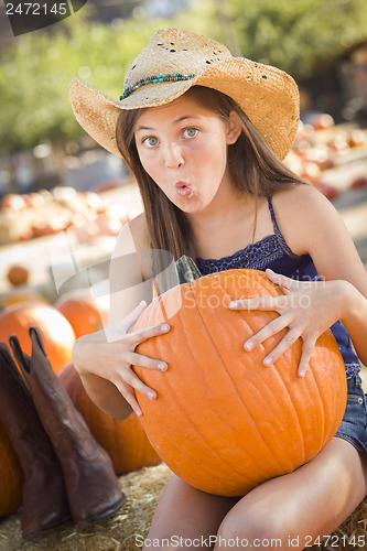 Image of Preteen Girl Holding A Large Pumpkin at the Pumpkin Patch
