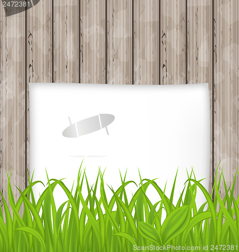 Image of Green grass and paper sheet on wooden texture