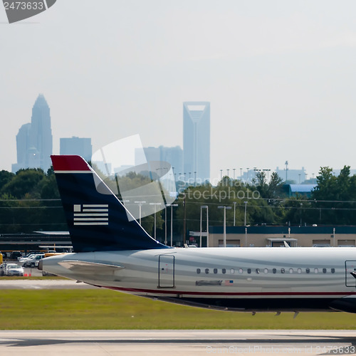 Image of Commercial jet on an airport runway with city skyline in the bac