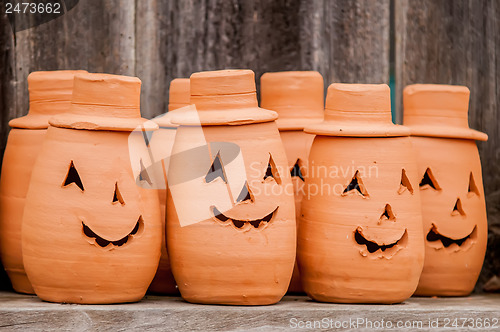 Image of clay pumpkins standing happy near the wood fence