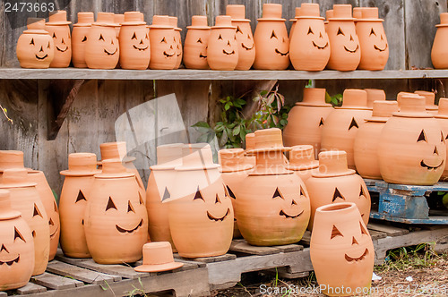 Image of clay pumpkins standing happy near the wood fence