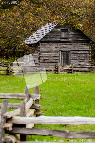 Image of Beautiful Autumn scene showing rustic old log cabin surrounded b
