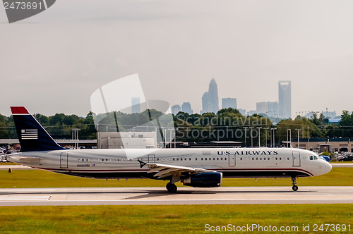 Image of Commercial jet on an airport runway with city skyline in the bac