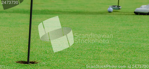 Image of Golf ball on a green, in front of the hole,