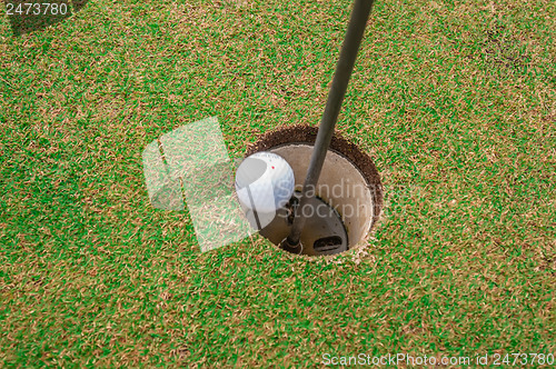 Image of Golf ball on a green, in front of the hole,