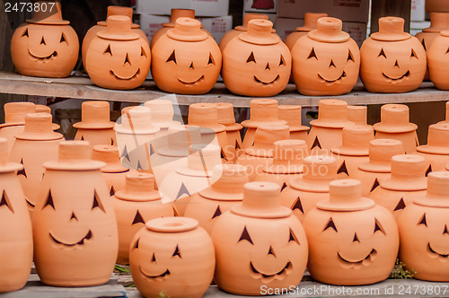 Image of clay pumpkins standing happy near the wood fence
