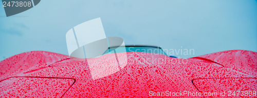 Image of red sports car wet from rain drops