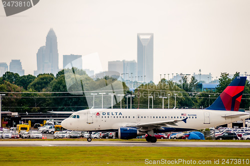 Image of Commercial jet on an airport runway with city skyline in the bac