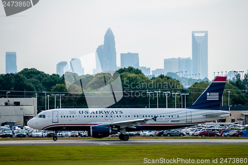 Image of Commercial jet on an airport runway with city skyline in the bac