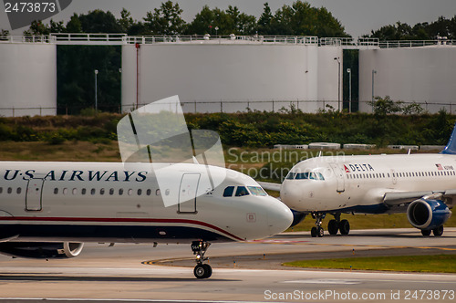 Image of Commercial jet on an airport runway with fuel tanks in back