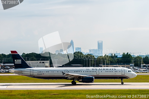 Image of Commercial jet on an airport runway with city skyline in the bac