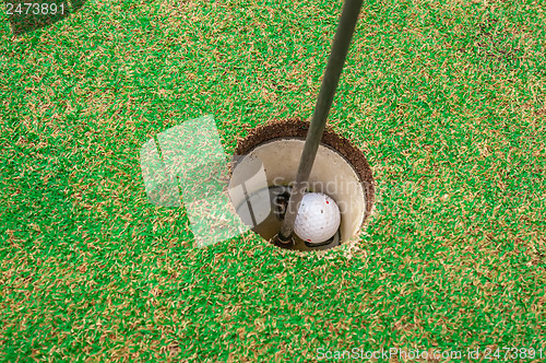 Image of Golf ball on a green, in front of the hole,