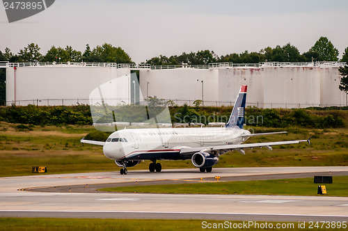 Image of Commercial jet on an airport runway with fuel tanks in back