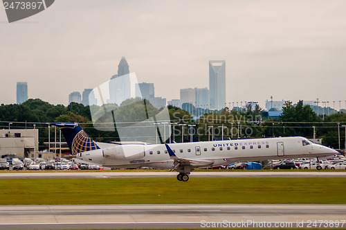 Image of Commercial jet on an airport runway with city skyline in the bac